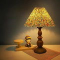 KAVYNZO bedside table lamp with a wood grain base and a pleated floral fabric lampshade emitting a warm glow.
